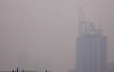 A worker stands atop a building under construction on a hazy day in Beijing
