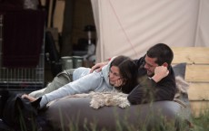 A couple relaxing with their dog outside their tent