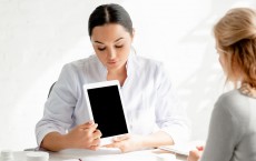 Dermatologist showing digital tablet with copy space to patient in clinic - stock image