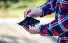 person in red blue and white plaid long sleeve shirt holding black leather bifold wallet